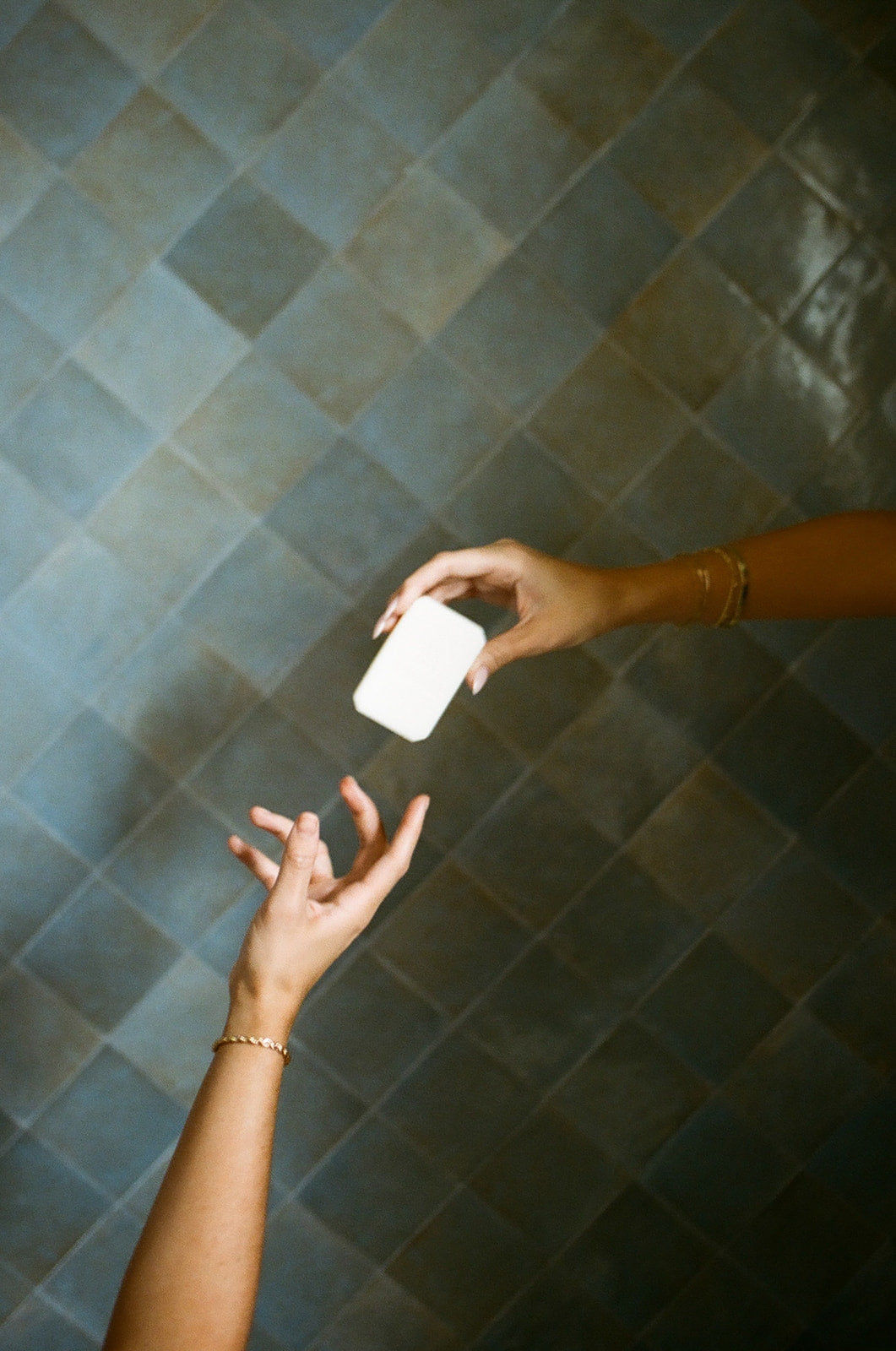 Hyaluronic+ Solid Shampoo Bar being held above hands in a stylish bathroom, representing plastic free hair care.