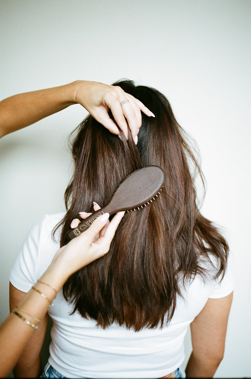 Person using Dry Detangling Hair Brush on long, shiny hair to minimize breakage and promote scalp care.