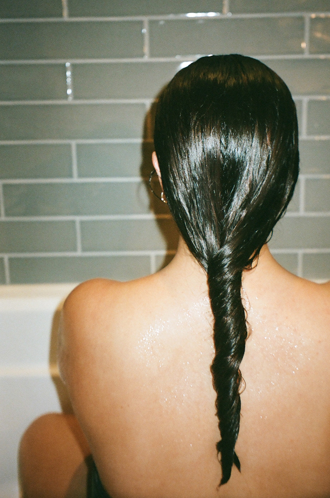 Back view of a woman with glossy braided hair, showcasing the benefits of Hyaluronic+ Solid Conditioner Bar.