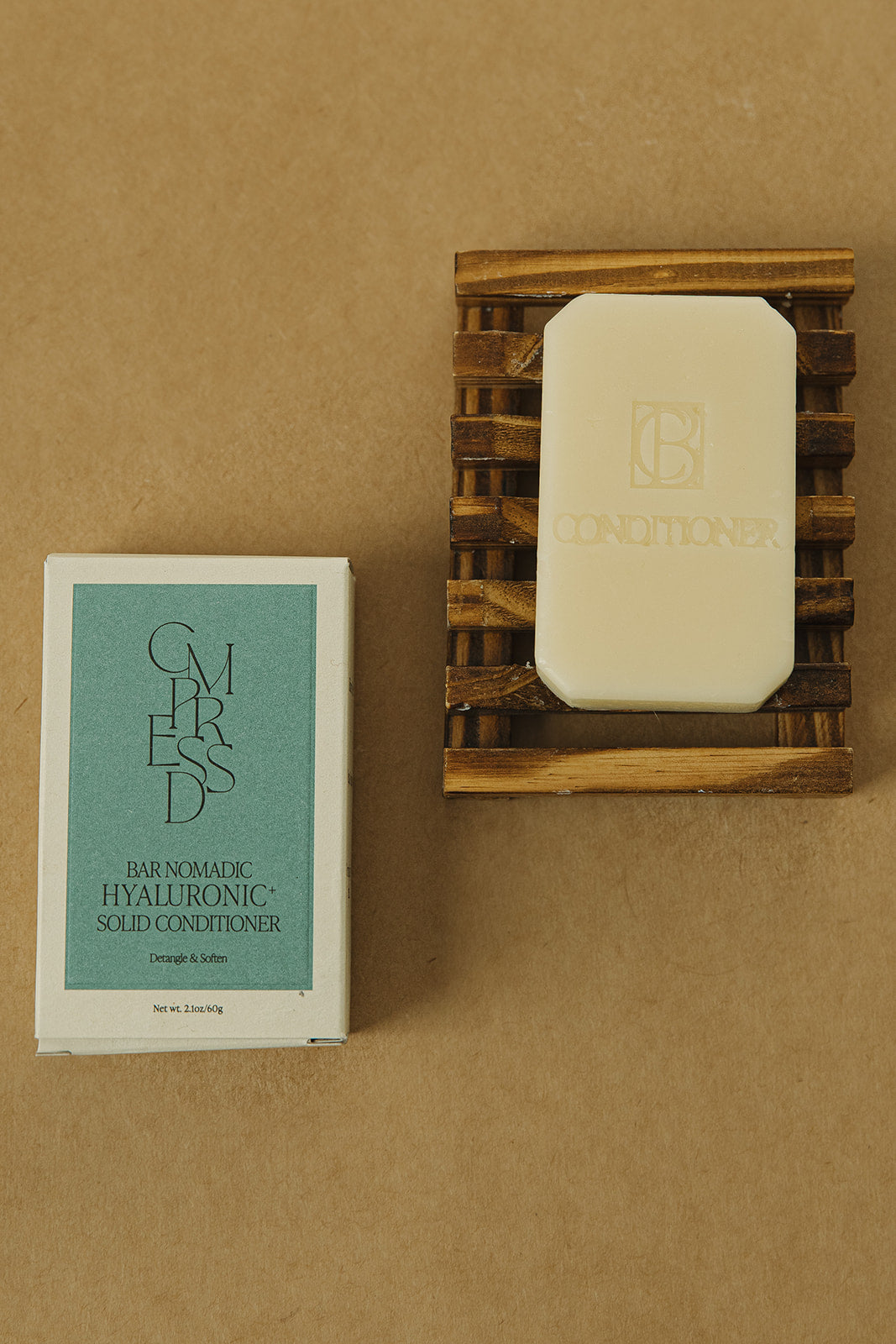 Hyaluronic+ Solid Conditioner Bar in eco-friendly packaging, showcasing plastic free hair care benefits. Conditioner bar on a wooden tray next to a white and green box.