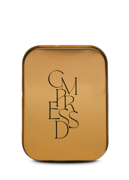 Gold travel tin with 'CMPRESSD' text on a white background